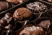 Load image into Gallery viewer, A close up view of a few milk chocolate orange buttercream with a few blurred out chocolates surrounding it.